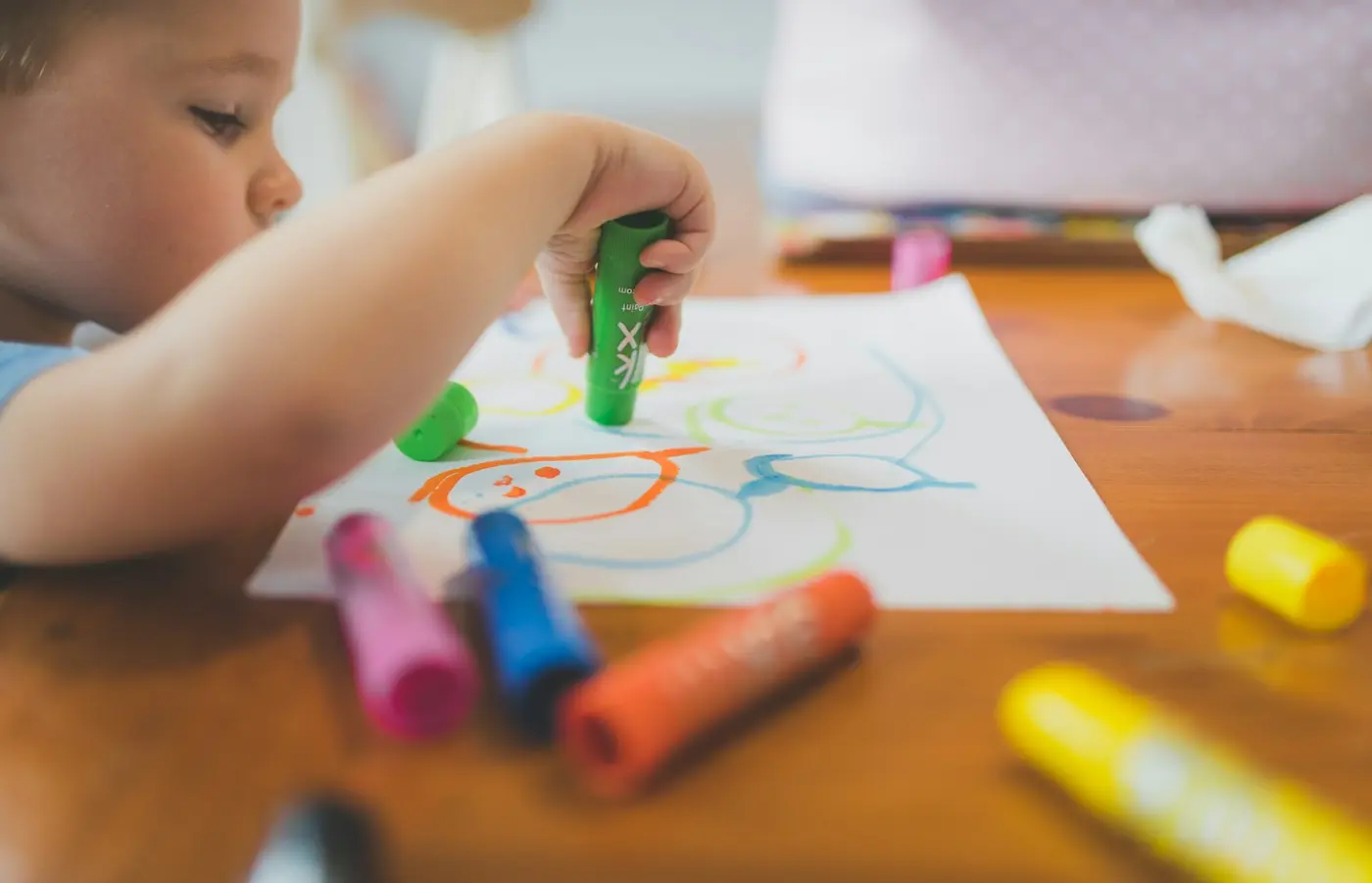 Child using crayons and washable paint at a table